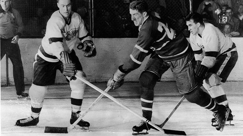 Canadian hockey player Red Kelly (left) of the Detroit Red Wings battles with Paul Masnick of the Montreal Canadiens for an airborne puck while Red Wing Marty Pavelich (right) skates in to join the action during the final game of the Stanley Cup in Detroit, Michigan, April 16, 1954. Detroit went on to win the game and the Cup. (Bruce Bennett Studios/Getty Images)
