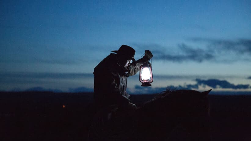 Cowboy on horse with lantern at dusk
