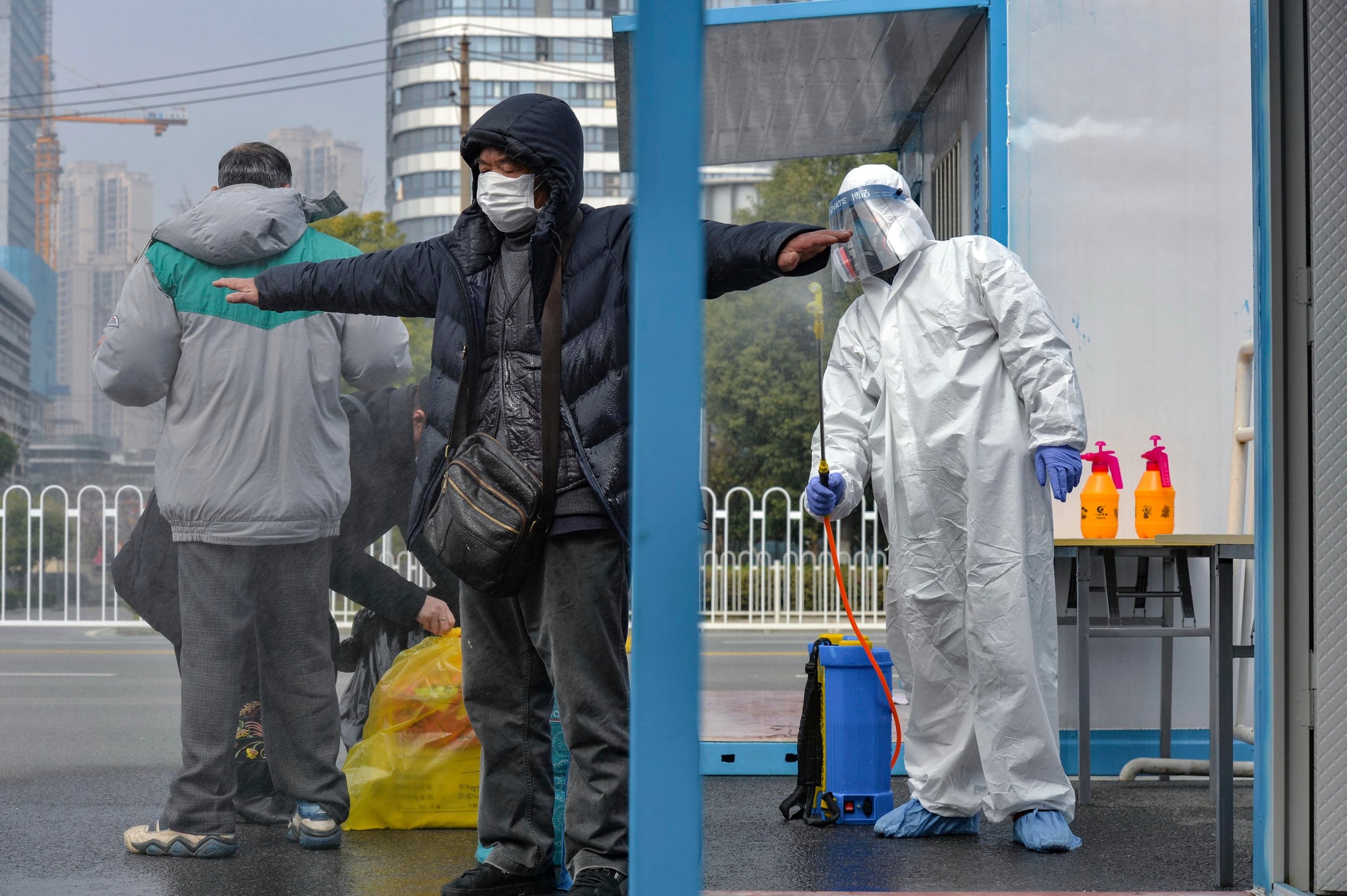 A worker disinfects a recovered COVID-19 patient departing a temporary hospital in Wuhan, Hubei province, China, on Feb. 22. (EPA/SHI ZHI CHINA OUT)