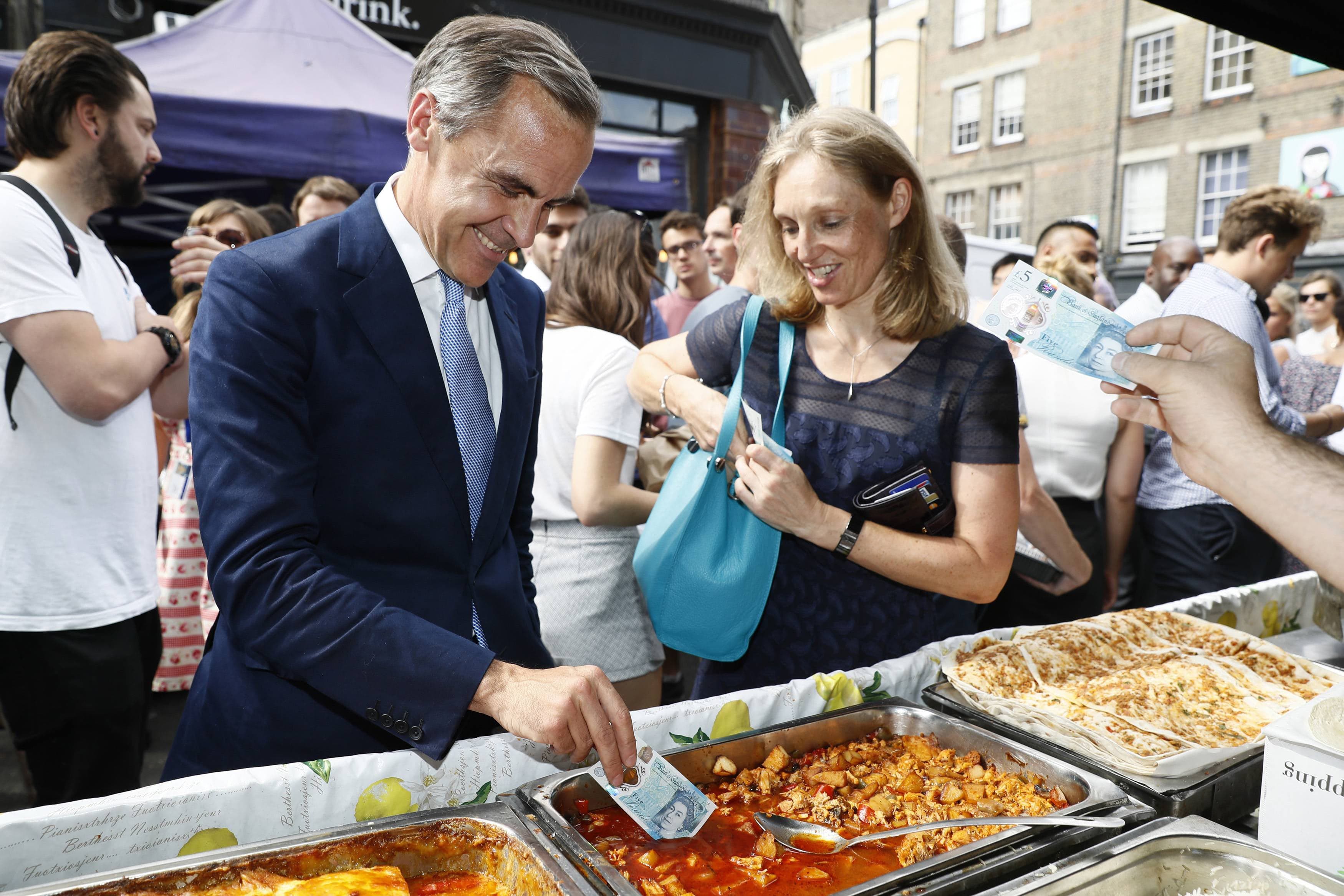 Bank of England governor Mark Carney tests a new polymer five pound note as he buys lunch at Whitecross Street Market on September 13, 2016 in London, United Kingdom. The new plastic note is designed to be more durable and features a portrait of former British Prime Minister Sir Winston Churchill. (Stefan Wermuth/Getty Images)