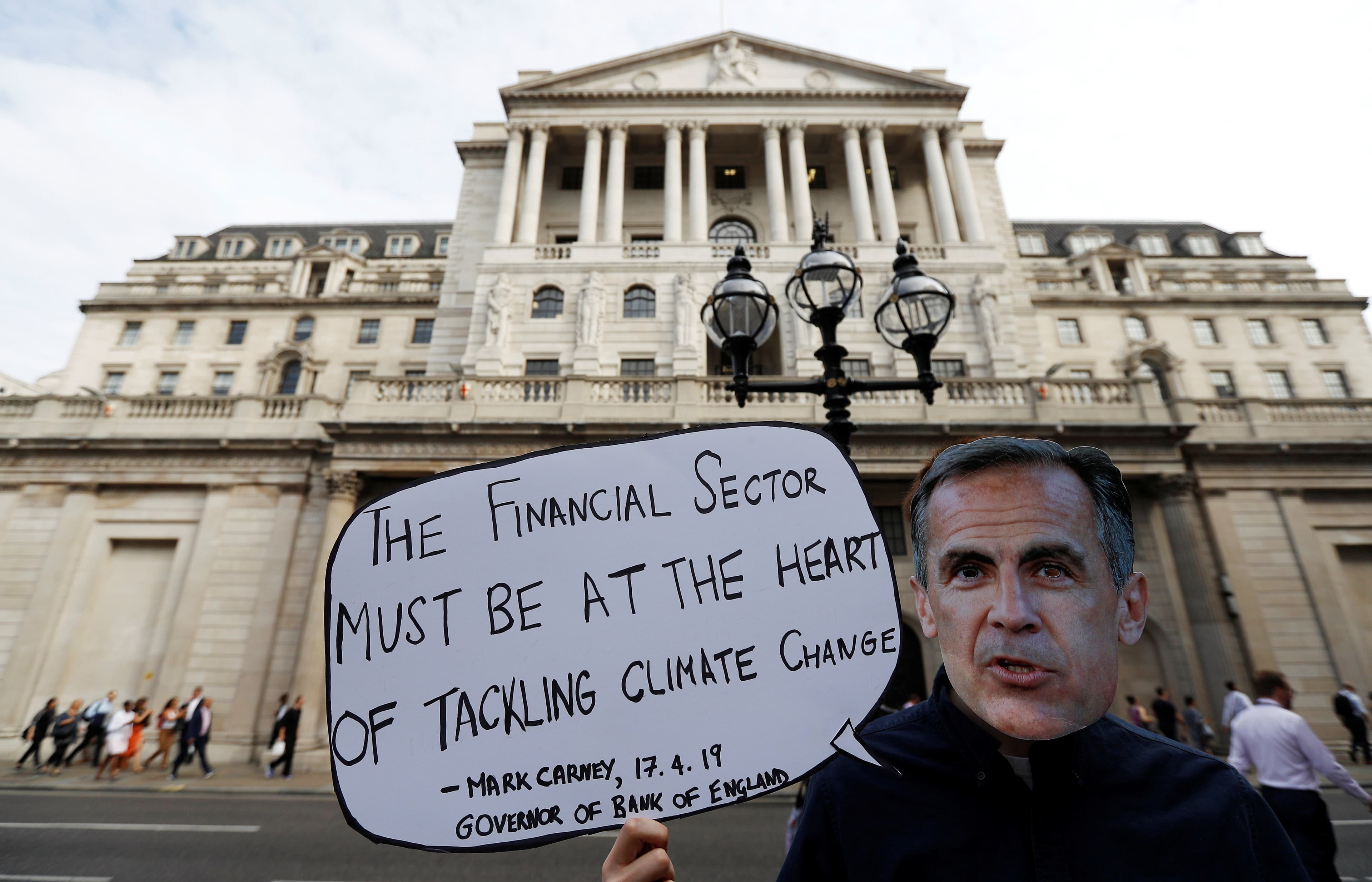 Environmental and banking system protestor wears a mask of Governor of the Bank of England, Mark Carney as they demonstrate outside the Bank of England demanding that the bank rule out investment in high-carbon sectors in London, Britain July 11, 2019. (Peter Nicholls/Reuters)