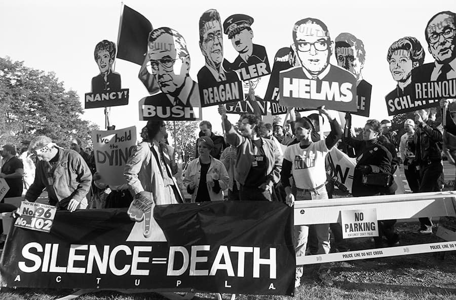 Members of AIDS activist group ACT UP (AIDS Coalition to Unleash Power) hold up signs of George W. Bush, Ronald Reagan, Nancy Reagan, Jesse Helms and other with the word "Guilty" stamped on their foreheads, along with a banner stating "Silence Equals Death" at a protest at the headquarters of the Food and Drug Administration (FDA) on October 11, 1988 in Rockville, Maryland. (Catherine McGann/Getty Images)