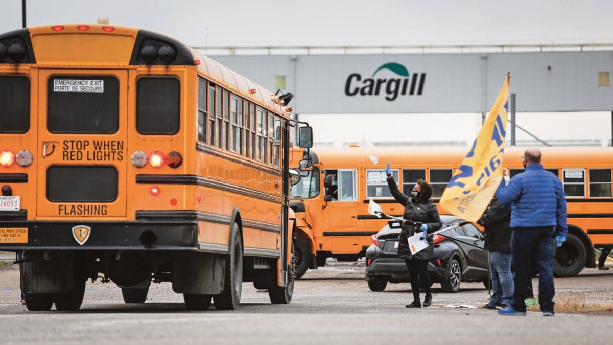 Union workers wave at shuttle buses carrying returning employees on May 4 (Jeff McIntosh/CP)