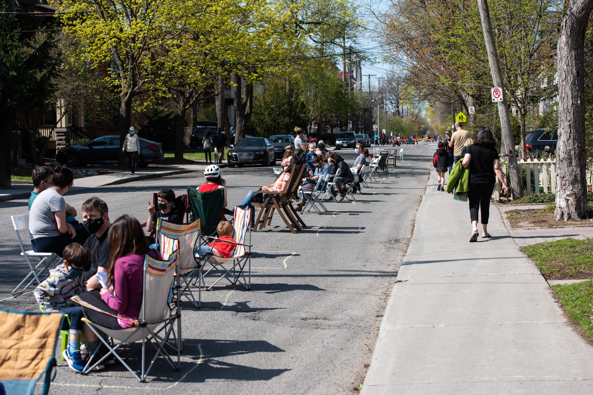 People sit along Fourth Avenue, closed to automobile traffic so people can sit for a period of observation after receiving their first COVID-19 vaccine from Dr. Nili Kaplan-Myrth's COVID-19 vaccine clinic, nicknamed "Jabapalooza," near her family medical clinic in Ottawa on Saturday, April 24, 2021. (Photograph by Justin Tang)