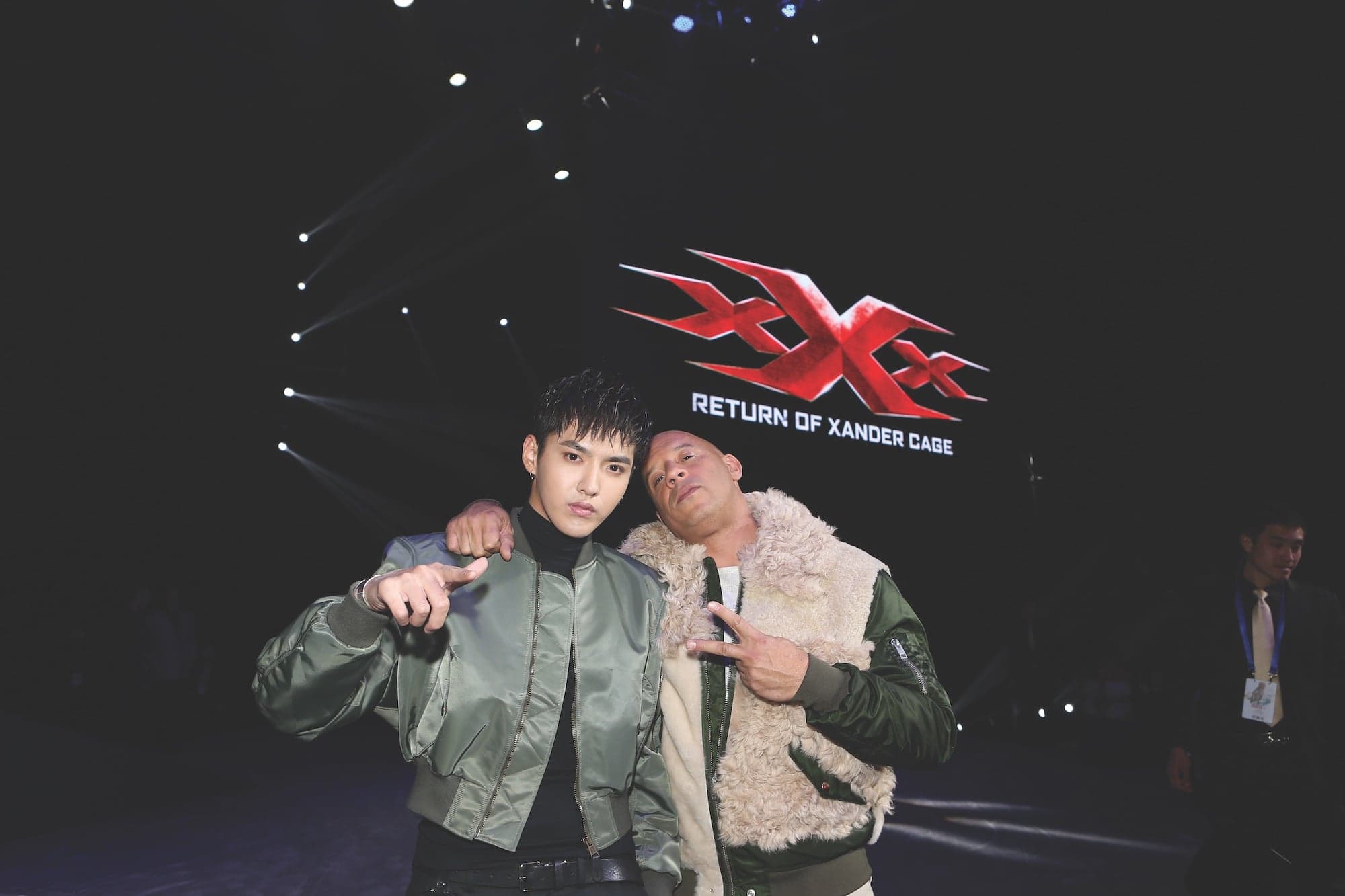 Two men stand in front of a sign for a movie