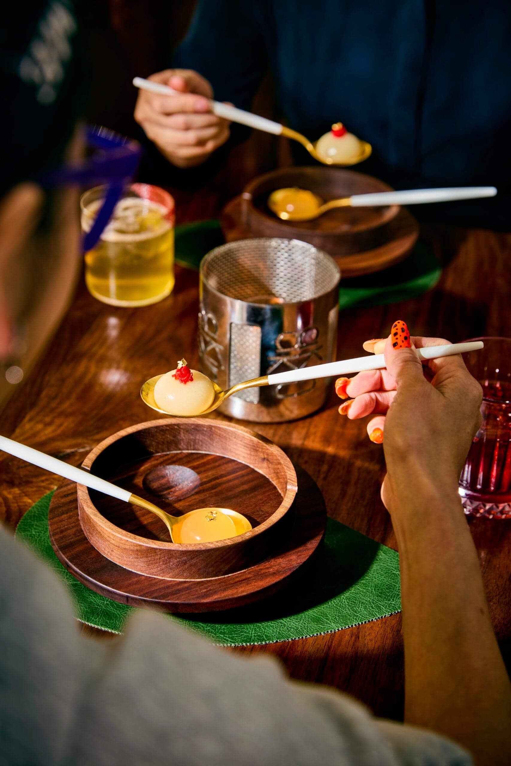 Hands scooping one-bite spheres from a table set with wooden dishes