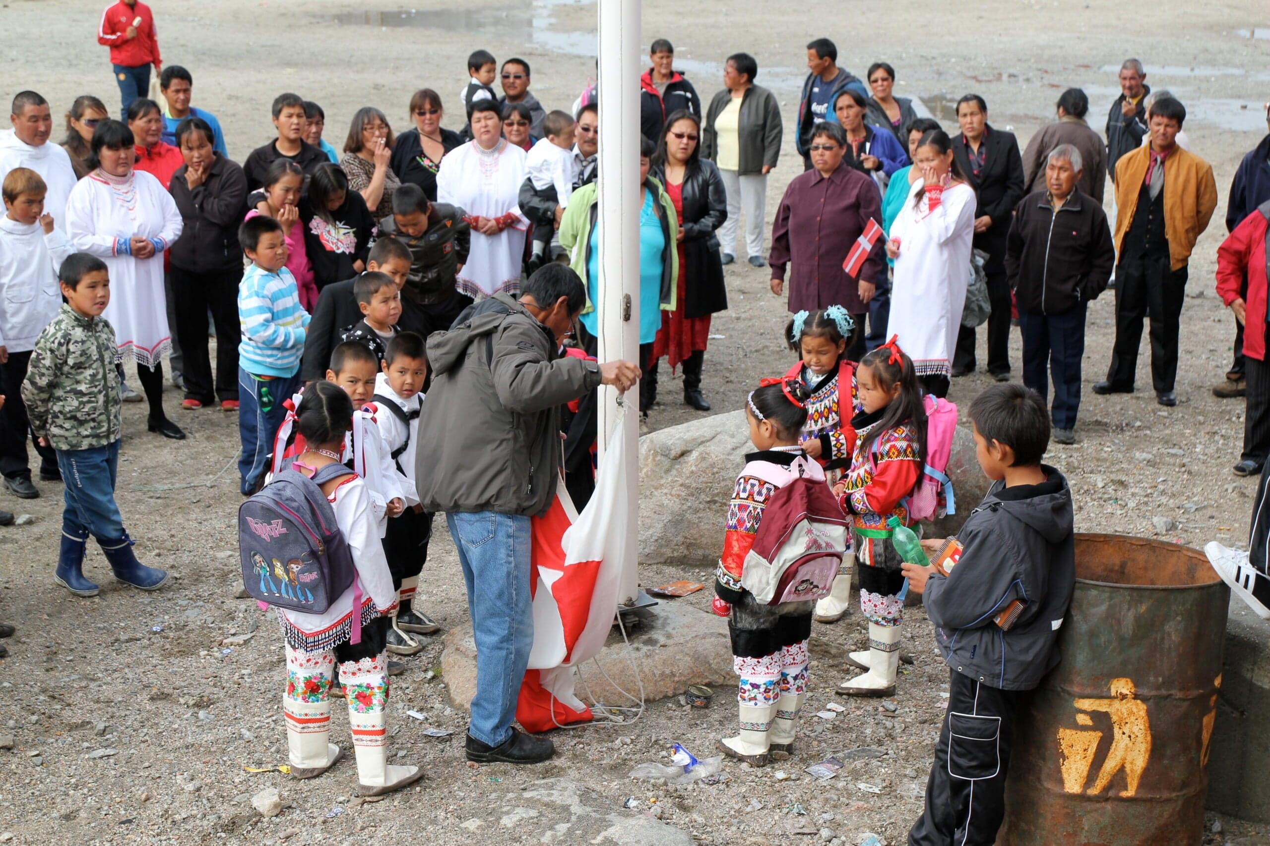 A group of kids gathered around a flagpole for a flag-raising ceremony