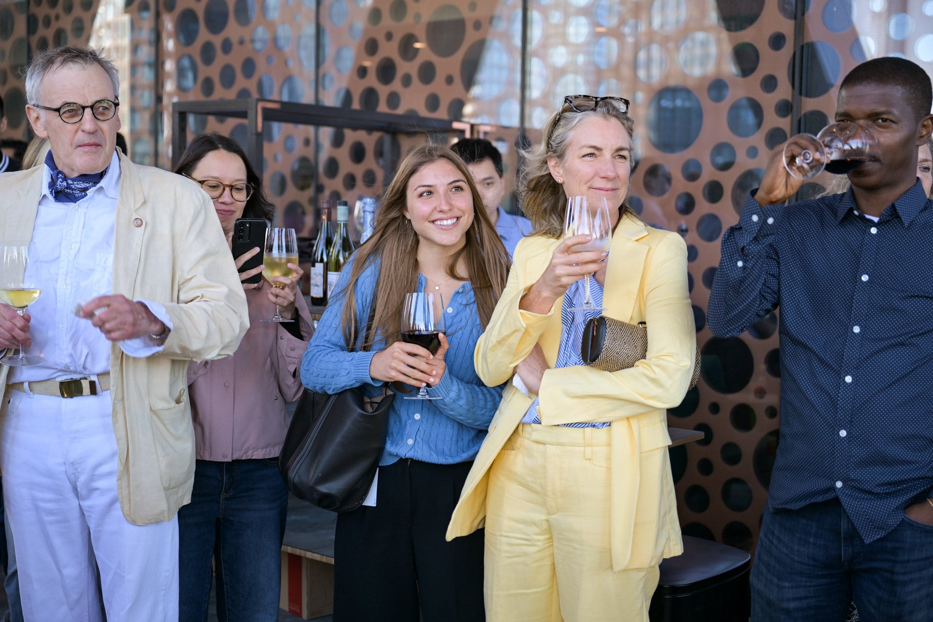 The guests watching the drag performance with glasses in their hands