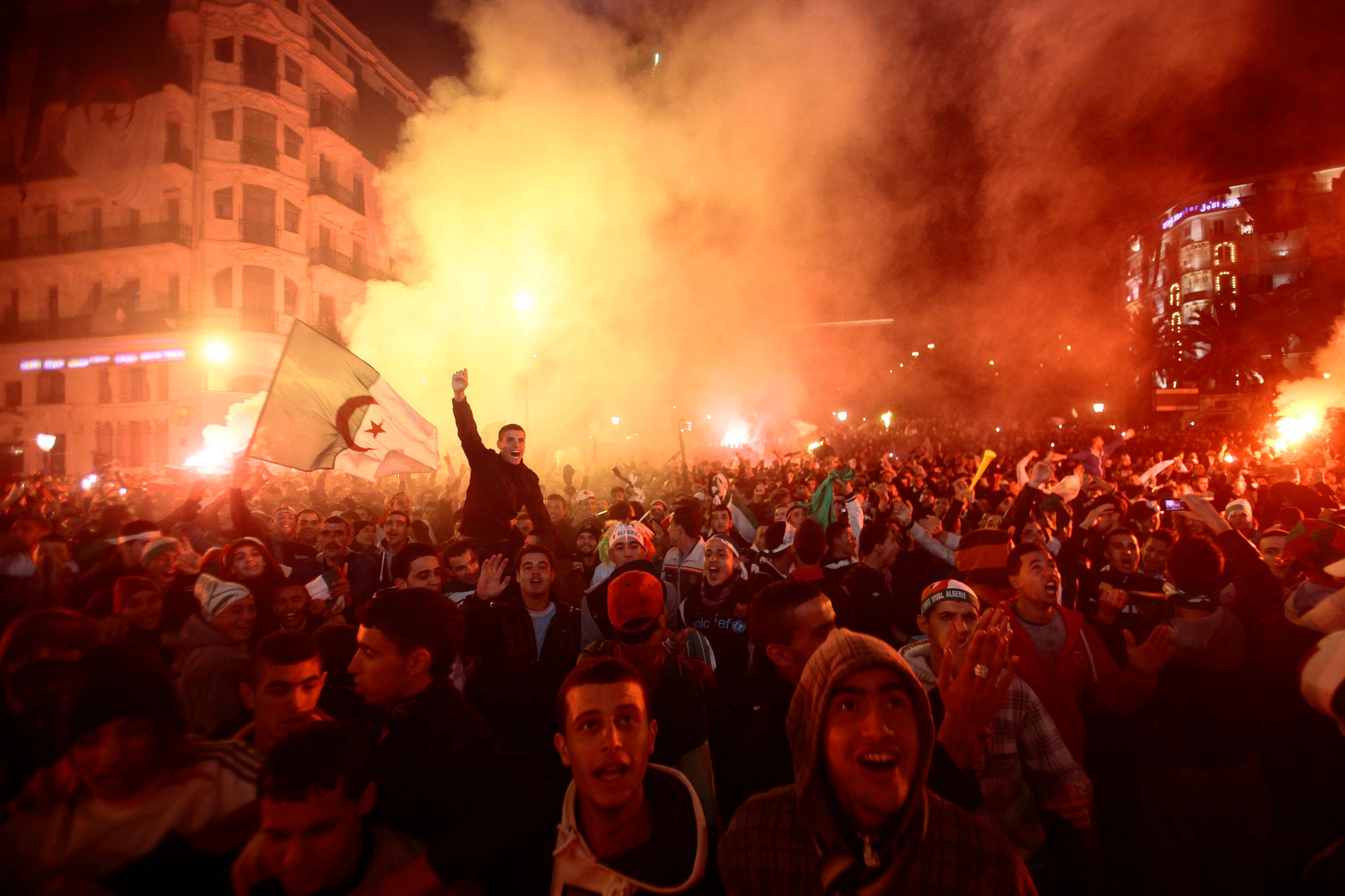Fans of Algeria&#8217;s soccer team hold the country&#8217;s national flag as they celebrate in downtown Algiers