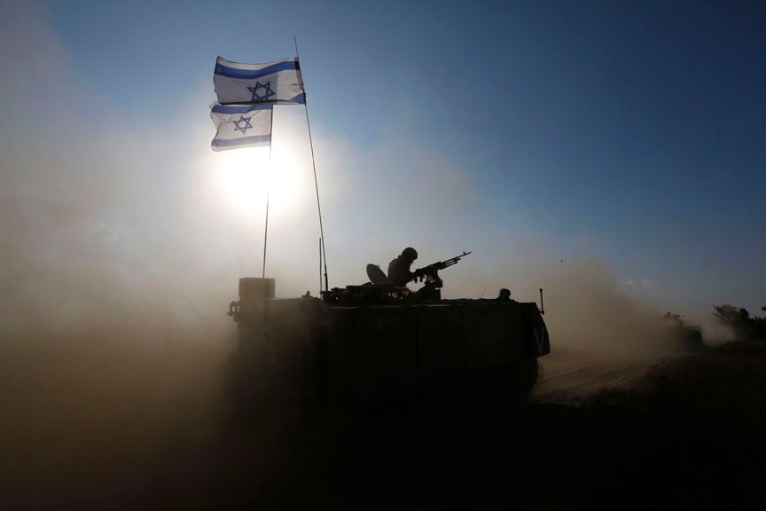 An Israeli soldier rides an armoured personnel carrier (APC) towards a staging area near the border with the Gaza Strip
