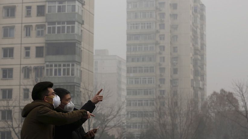 Men wearing protective masks talk on a street on a heavily polluted day in Beijing