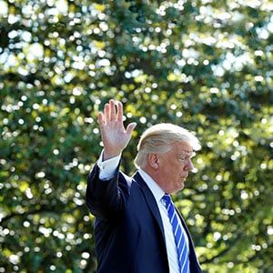 U.S. President Donald Trump waves as he walks on the South Lawn of the White House in Washington