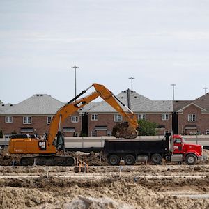 Construction workers build homes on a lot in Toronto