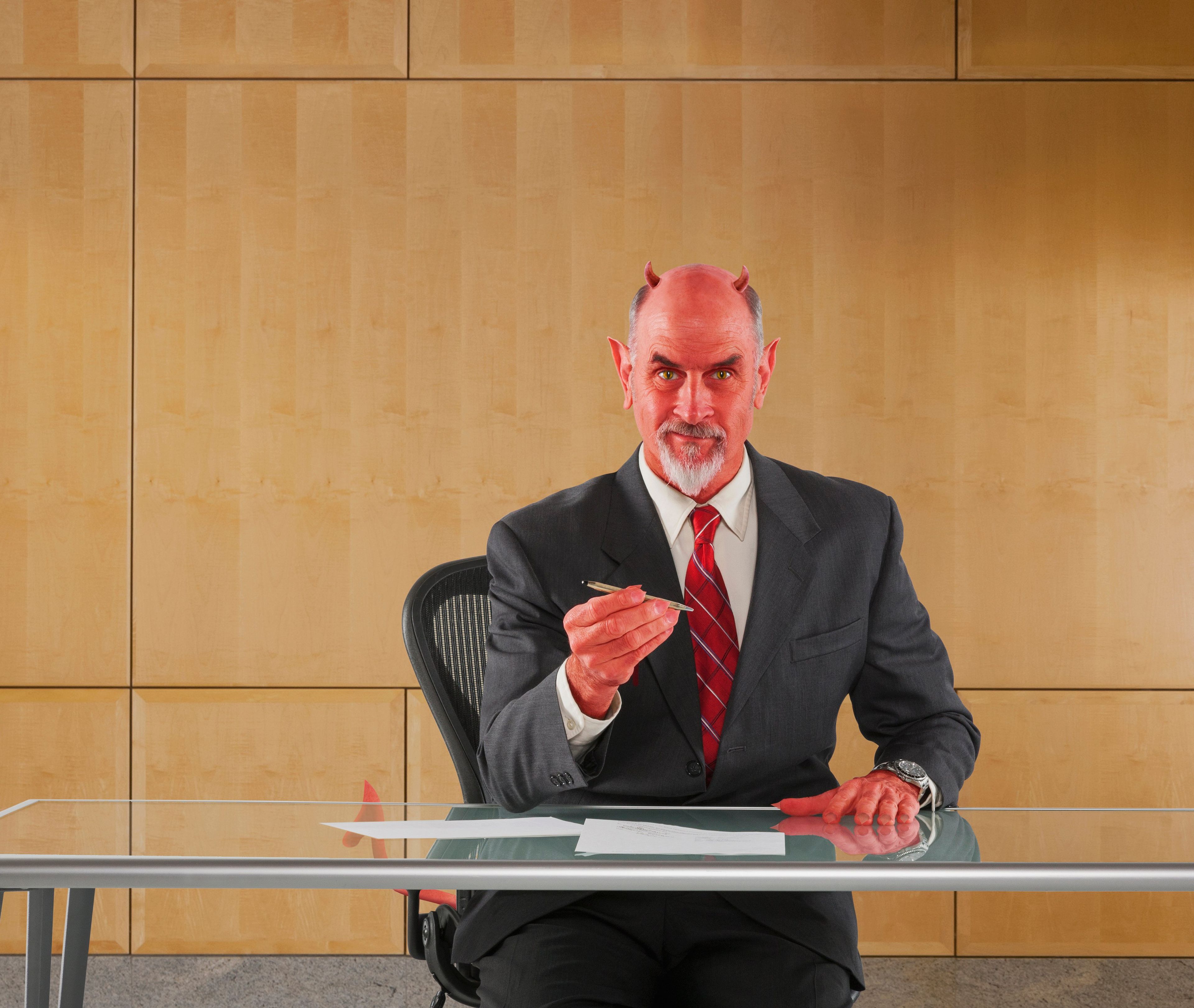 Caucasian businessman in devil costume offering pen to sign contract