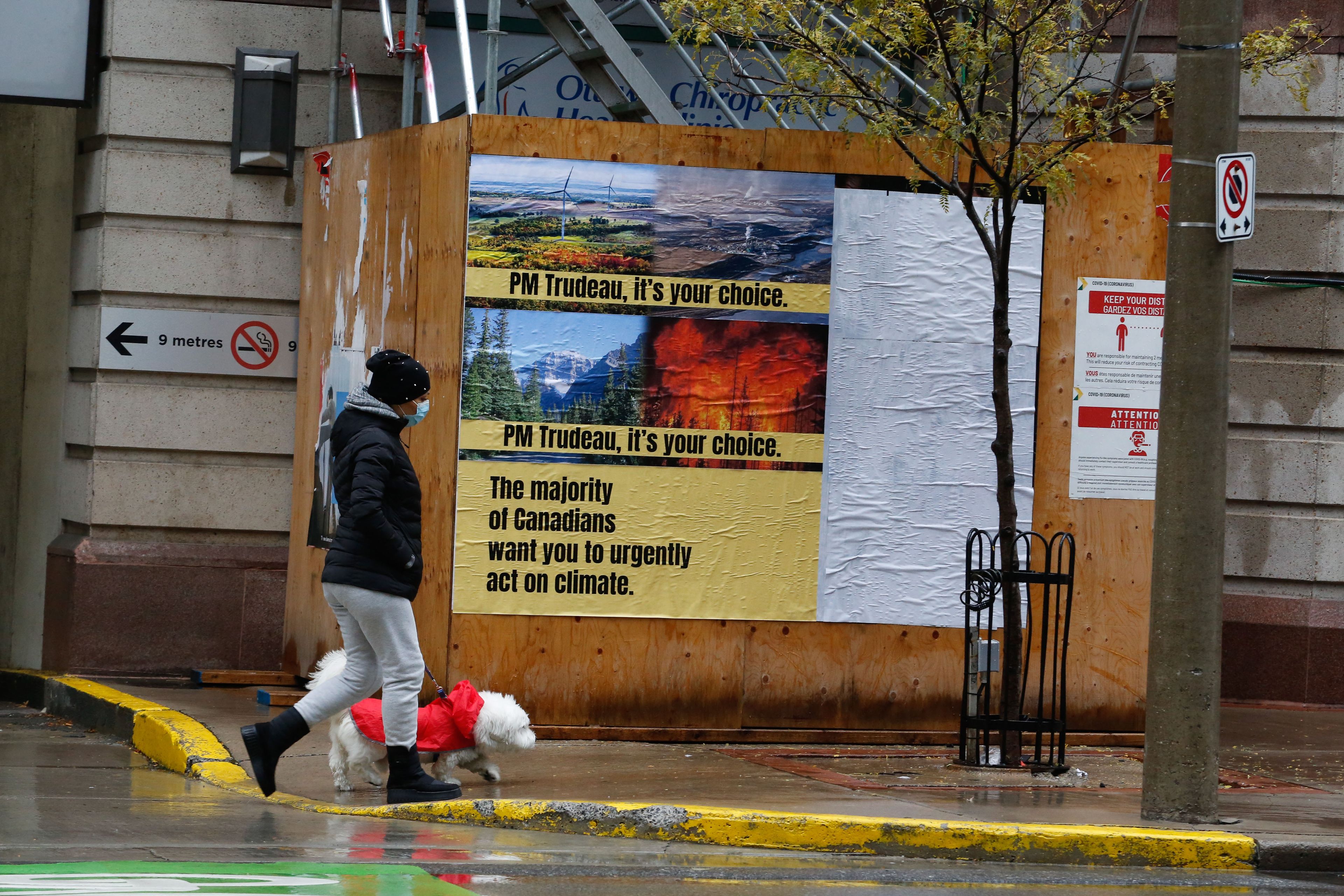 A pedestrian walks by a poster installation in Ottawa on Oct. 31, 2021 (CP)