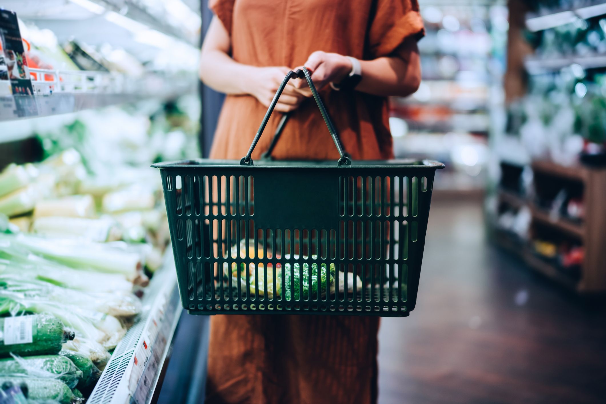 Cropped shot of young woman carrying a shopping basket, grocery shopping for fresh organic fruits and vegetables in supermarket. Green living. Healthy eating lifestyle