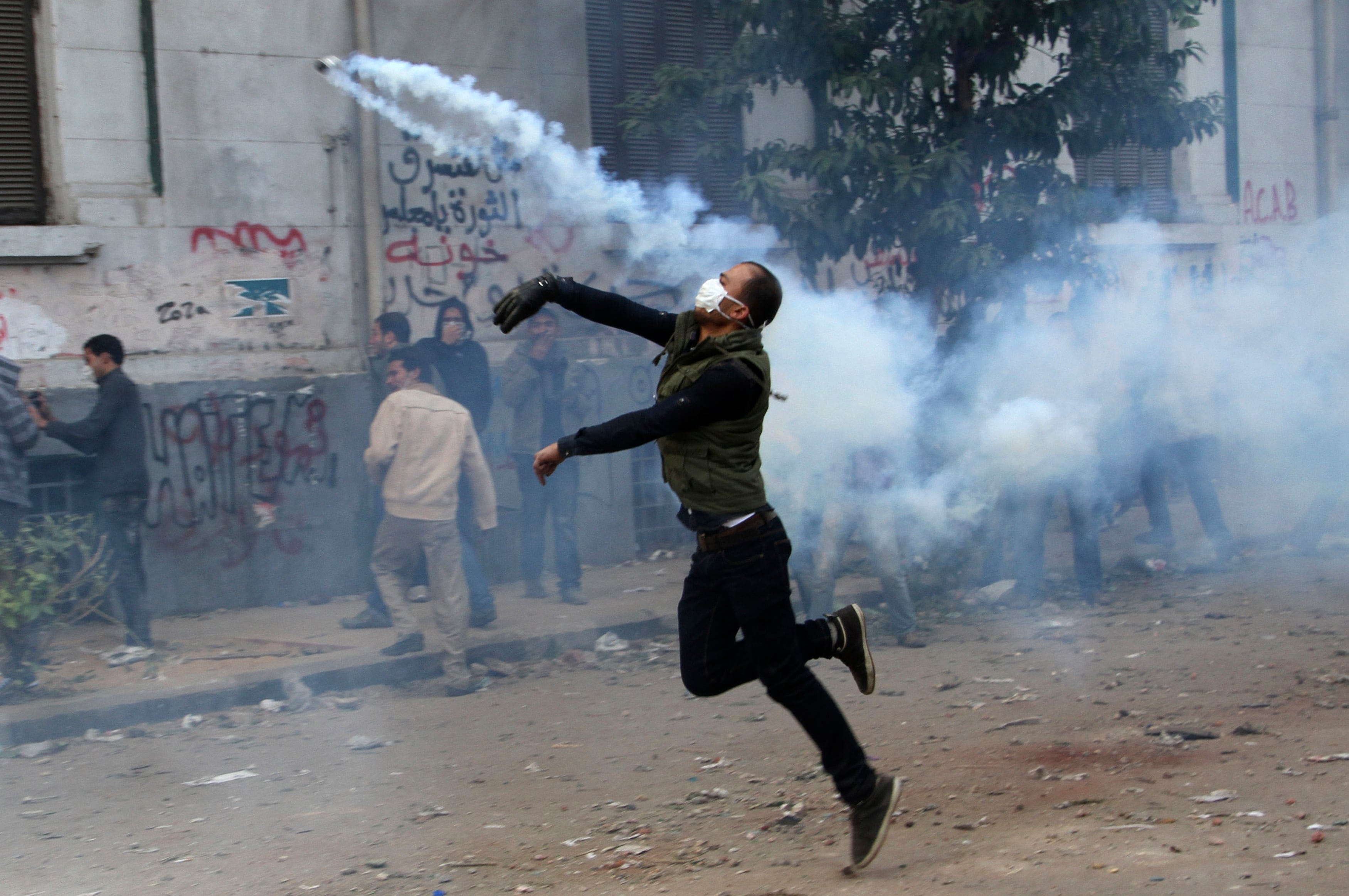 A protester throws a tear gas canister near Tahrir Square in Cairo