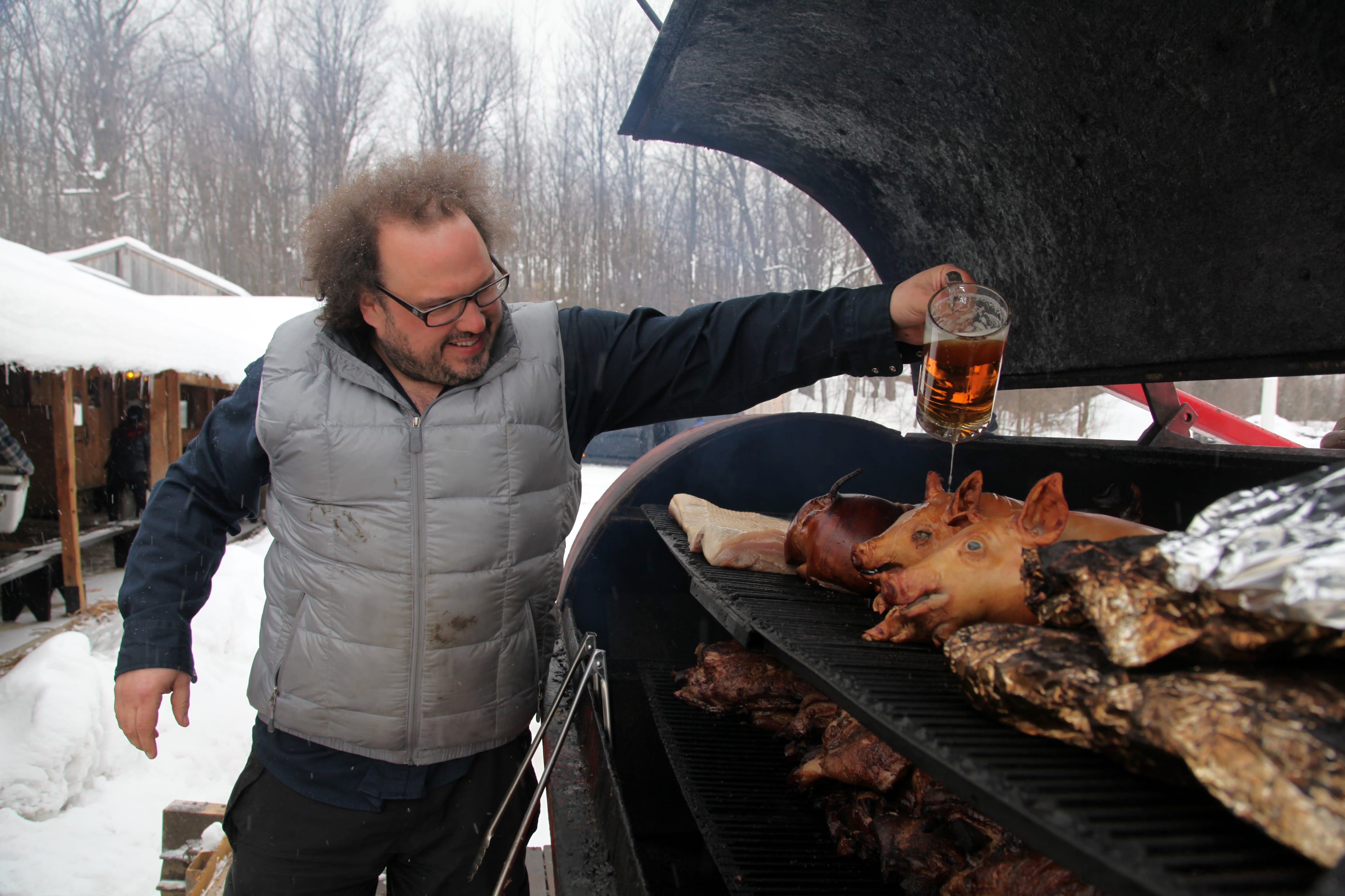 Picard pouring beer over the suckling pigs in the smoker