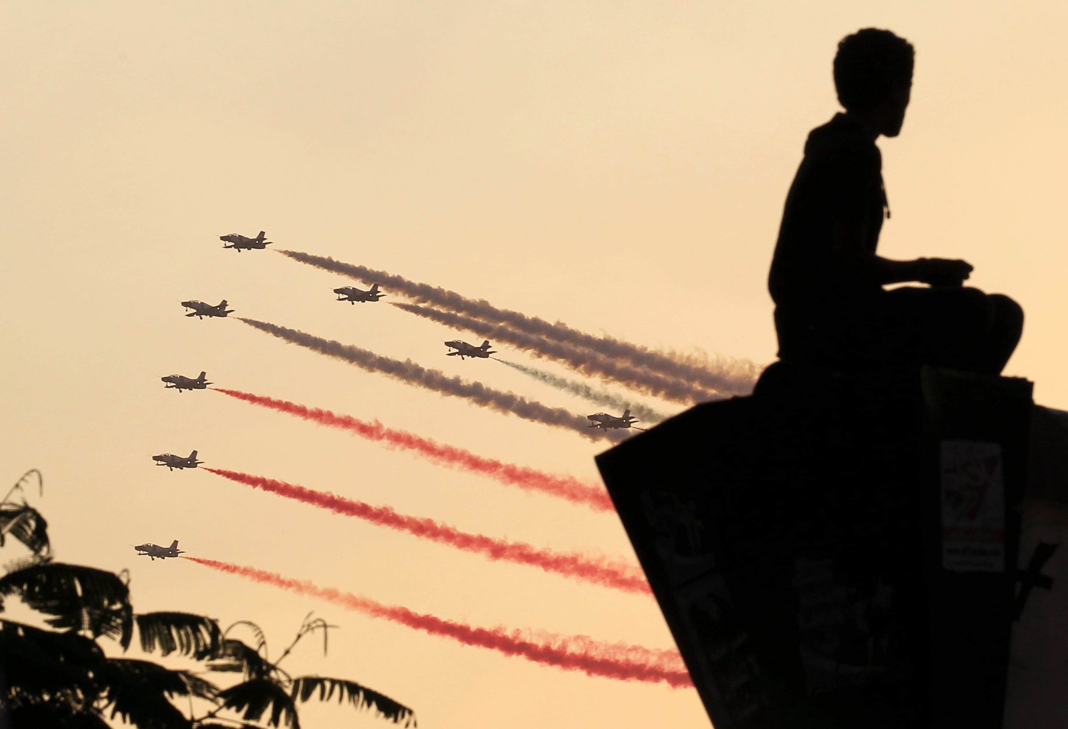 A man is silhouetted as Egyptian military jets fly in formation over Tahrir square in Cairo