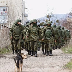 Armed men, believed to be Russian servicemen, walk outside a Ukrainian military base in Perevalnoye