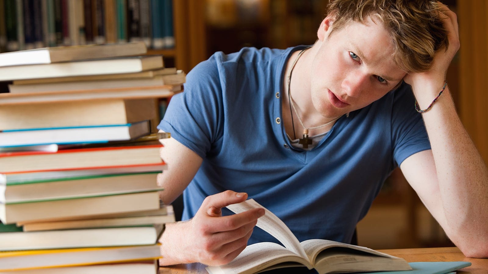 Tired man with a book in a library.
