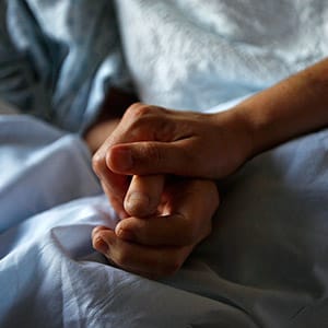 A woman holds the hand of her mother who is dying from cancer during her final hours at a palliative care hospital in Winnipeg