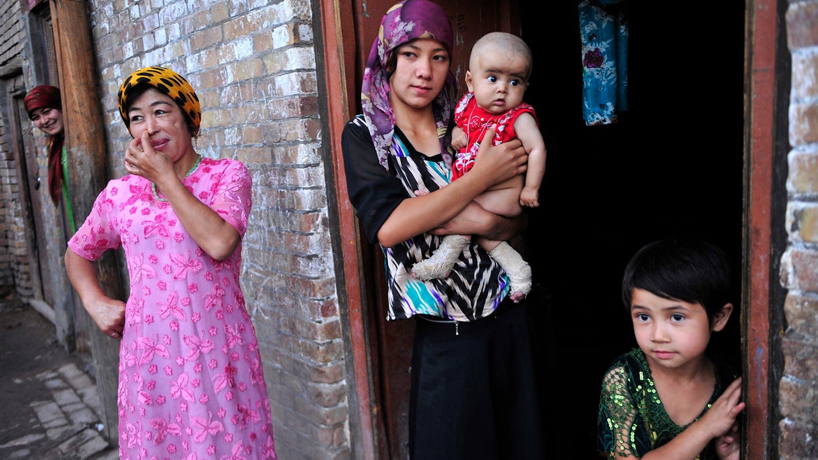 An ethnic Uighur woman (centre) hugs her son as she stands outside her house with her daughter and neighbours at an old residential area of Kashgar, Xinjiang in the Uighur Autonomous Region. (Rooney Chen/Reuters)
