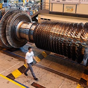 A worker walks past a gas turbine under construction at the gas turbines production unit of the General Electric plant in Belfort