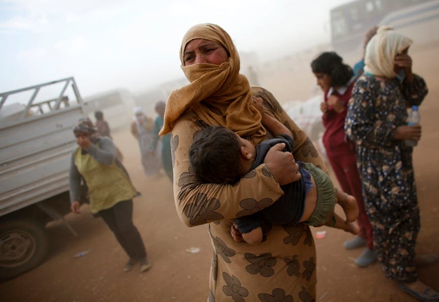 A Kurdish Syrian refugee waits for transport during a sand storm on the Turkish-Syrian border near the southeastern town of Suruc