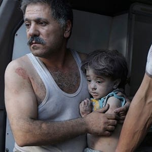 A man holds a child that survived from under rubble, after what activists claim was five air strikes by forces loyal to Syria's President Bashar al-Assad in Douma