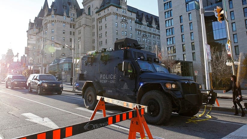 A RCMP vehicle passes the Fairmont Chateau Laurier as it leaves a secure area downtown following shootings in Ottawa
