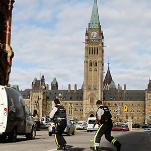 Armed RCMP officers race across a street on Parliament Hilll following a shooting incident in Ottawa