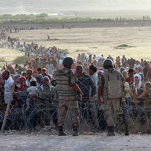 Turkish soldiers stand guard as Syrians wait behind the border fences near the southeastern town of Suruc in Sanliurfa province