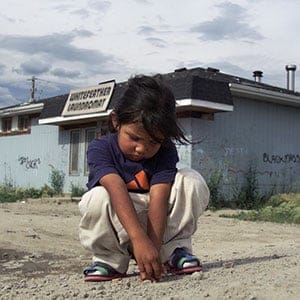 Pikangikum_SadGirl50-07/24/01-A sad young girl plays by herself on a dusty road in Pikangikum. Pikan