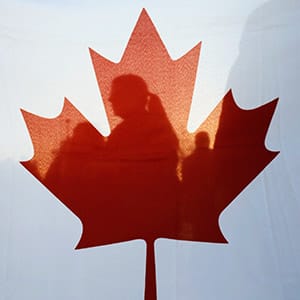 Israelis are silhouetted behind a Canadian flag at a rally to thank Canada's PM Harper for his support of Israel during his visit at the Israeli parliament in Jerusalem