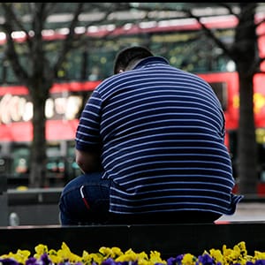 A man sits on a wall in the Canary Wharf financial district of London