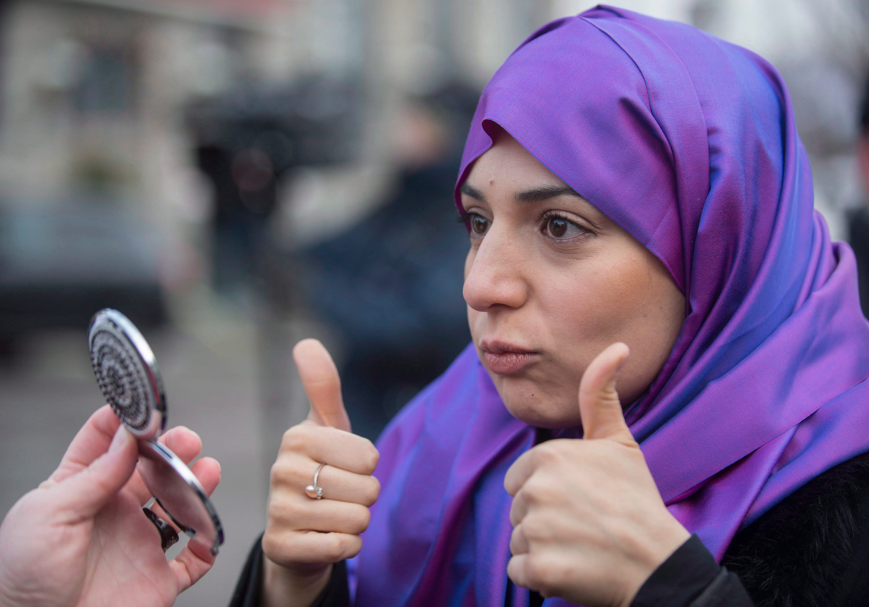 Nariman Eldoraini gives a thumbs up as she checks her Niqab in a mirror during a gathering in Montreal, Sunday, January 12, 2014, to oppose the proposed Quebec Values Charter. (Graham Hughes/CP)