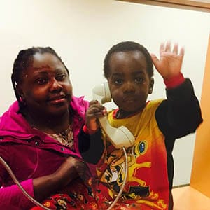 Alpha Anawa holds the phone during a visit at Toronto's Immigration Holding Centre, where he lives with his mother Glory (left). Photograph by Rachel Browne.