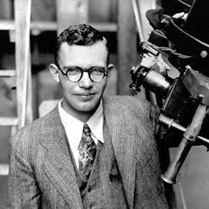 In this 1931 file photo, Clyde Tombaugh poses with the telescope through which he discovered the Pluto at the Lowell Observatory on Observatory Hill in Flagstaff, Ariz. On Tuesday, July 14, 2015, NASA's New Horizons spacecraft, carrying a small canister with his ashes, is scheduled to pass within 7,800 miles of Pluto which he discovered 85 years ago. (AP)
