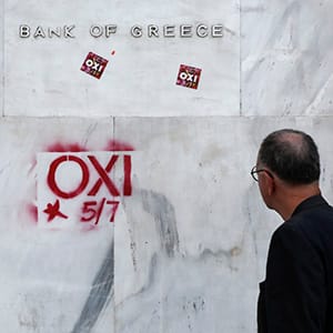 A pedestrian looks at anti-austerity graffiti reading "OXI" or "NO" sprayed onto the wall of the headquarters of Greece's central bank in Athens, Greece, on Thursday, July 2, 2015. Greek voters are almost evenly split heading into a referendum in three days that European leaders said could plunge the country into economic darkness. Photographer: Yorgos Karahalis/Bloomberg via Getty Images