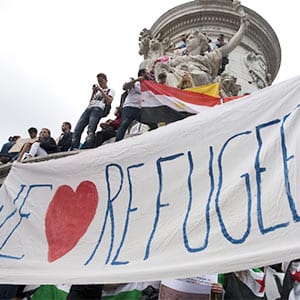 People hold a banner that says "We love refugees" as they take part in a demonstration asking for a change in the refugee policy in Europe on the Republique square in Paris, France, September 5, 2015.Philippe Wojazer/Reuters