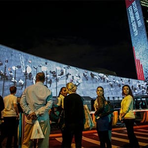 NEW YORK, NY - SEPTEMBER People watch Big scale projections over the general assembly building at United Nations headquarters on September 22, 2015 in New York City.  The projections and peoples  voices are seen during the celebration of UN70 and visually depict the 17 Global Goals.  
Kena Betancur/Getty Images for Global Goals