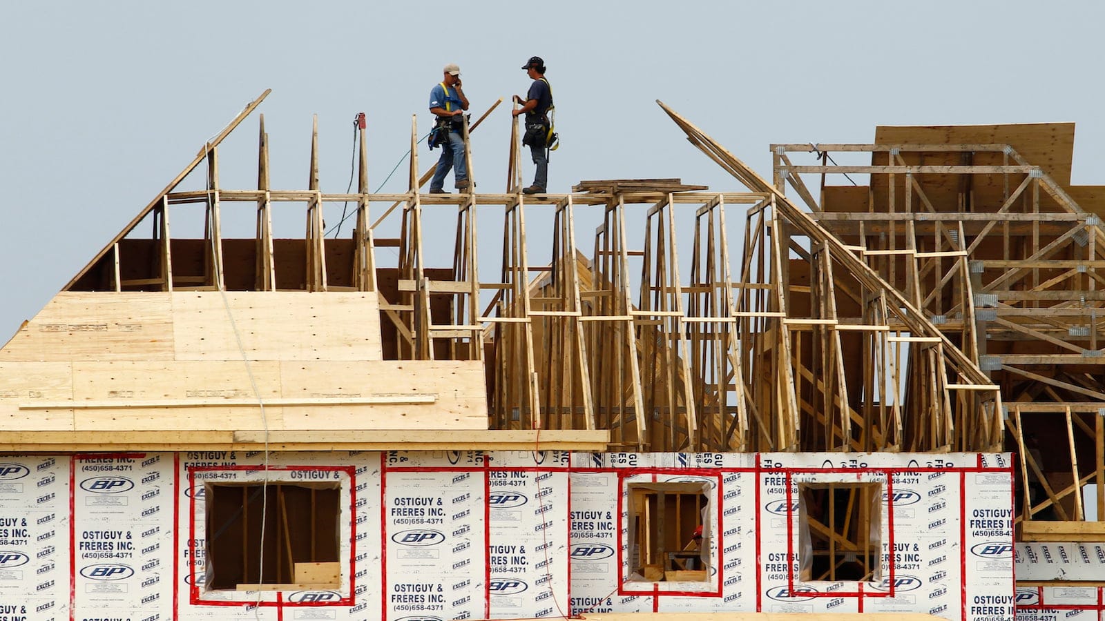 Builders work on the the roof of a new home under construction in the Montreal suburb of Brossard, August 10, 2010. Canadian housing starts fell in July for a third straight month and new home prices rose less than expected in June, further evidence that the housing boom that helped drive the country's recovery from recession is starting to stall. REUTERS/Shaun Best   (CANADA - Tags: BUSINESS) - RTR2H7WP