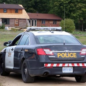 Flowers are placed at the entrance of a driveway with Ontario Provincial Police cruisers at a house near, Cormac, Ont., one of three crime scenes, Wednesday September 23, 2015. A 57-year-old man has been charged with three counts of first-degree murder in the separate slayings of three women whose deaths sparked a lockdown and manhunt in an ordinarily peaceful area of eastern Ontario on Tuesday. THE CANADIAN PRESS/Fred Chartrand