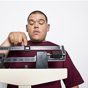MODEL RELEASED Teenage (16-17) boy using weight scales. (West Coast Surfer/Mood Board/Rex Features/CP