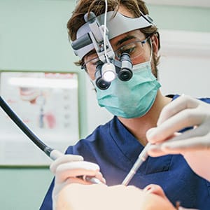 Dentist with microscope glasses during a root canal intervention. (Alejandro Moreno de Carlos/Stocksy)