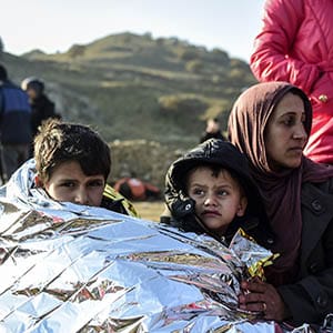 A Syrian family waits after arriving on the Greek island of Lesbos along with other migrants and refugees, on November 17, 2015, after crossing the Aegean Sea from Turkey.  At least eight people drowned when a boat carrying migrants from Turkey sank off the Greek island of Kos, the coastguard said on November 17, 2015. They were the latest of nearly 3,500 deaths at sea this year among people making desperate bids to flee war and poverty and to reach Europe, according to UN figures. European leaders tried to focus on joint action with Africa to tackle the migration crisis, as Slovenia became the latest EU member to act on its own by barricading its border. AFP PHOTO/BULENT KILIC        (Photo credit should read BULENT KILIC/AFP/Getty Images)