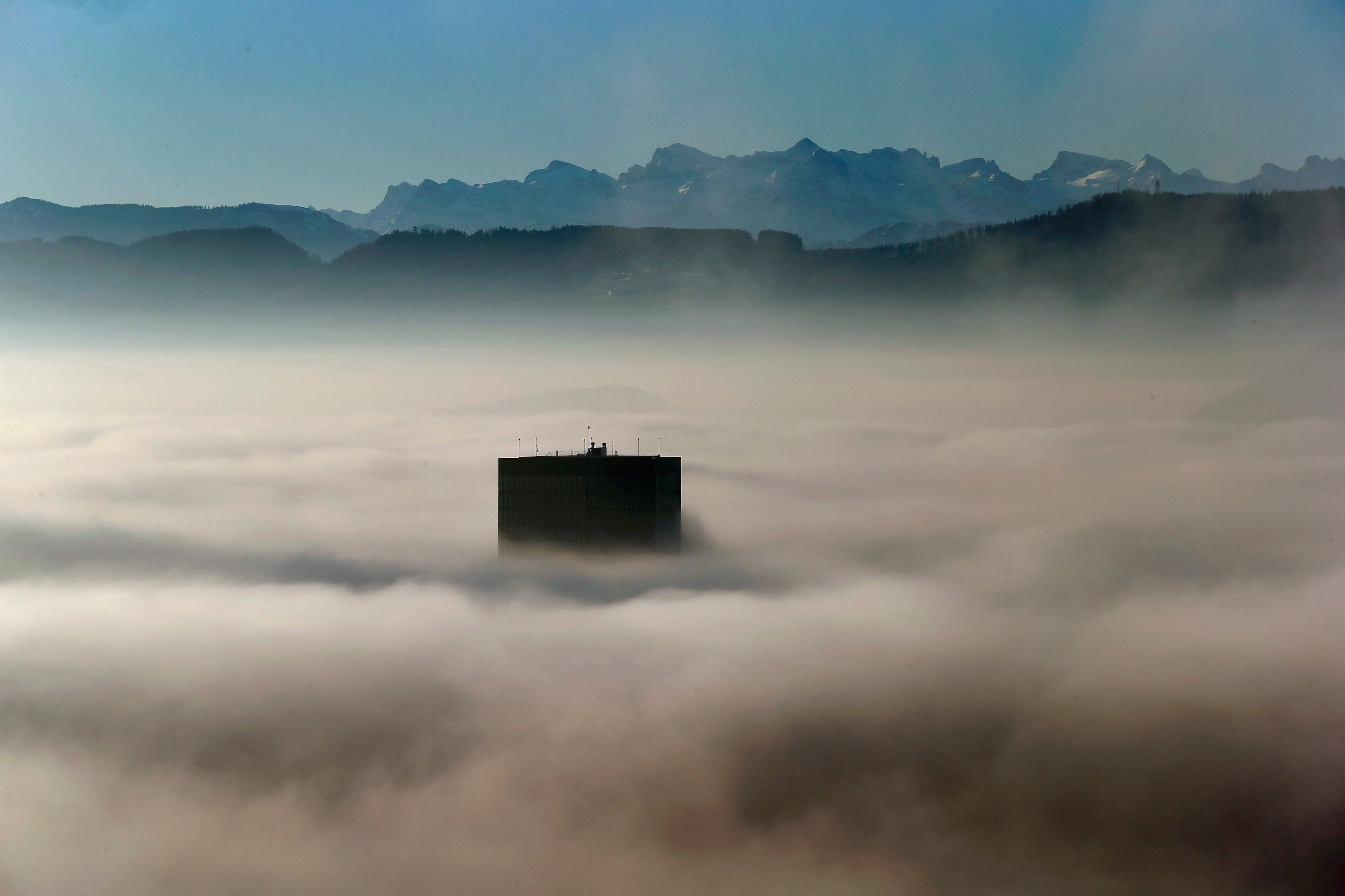 The top of Switzerland's highest skyscaper the Prime Tower (126 metres /413 ft) peeps through the fog in front of the Swiss Alps, early morning in Zurich, Switzerland December 7, 2015.  (Arnd Wiegmann/Reuters)