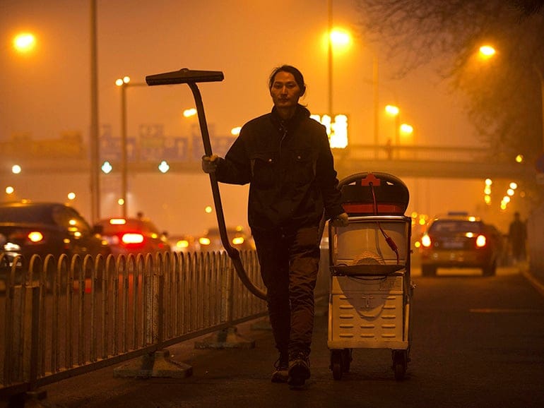 Chinese artist Wang Renzheng demonstrates the use of his industrial shop-vac alongside a highway in Beijing, Tuesday, Dec. 1, 2015. Wang spent 4 hours per day for 100 days vacuuming the Beijing air with an industrial shop-vac, then baked the accumulated dust and pollutants into a brick. (Mark Schiefelbein/AP)