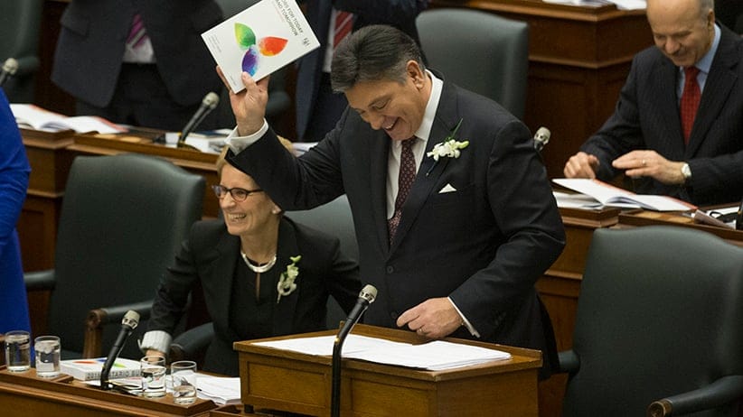 Minister of Finance Charles Sousa (right) shows off the budget to the Opposition benches as Premier Kathleen Wynne looks over the aisle. The Ontario Liberals table the budget in the Legislature. (Rick Madonik/Toronto Star/Getty Images)
